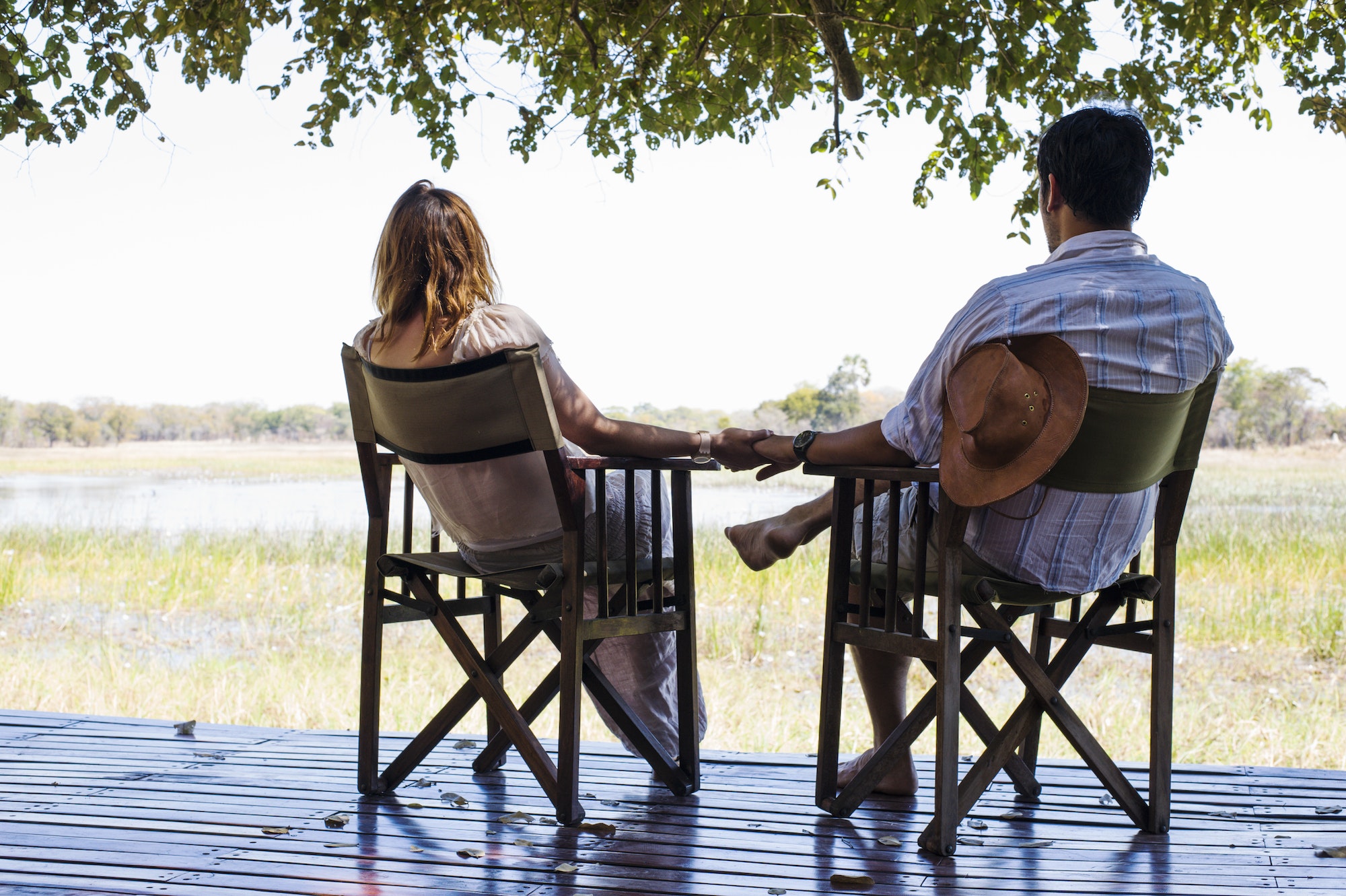 Romantic couple holding hands whilst sitting at safari lodge, Kafue National Park, Zambia